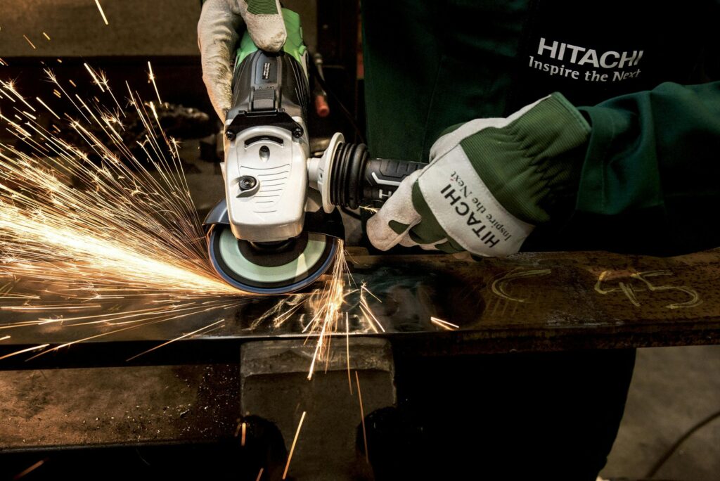 Uhistule Close-up of a skilled worker using a grinder with sparks flying in a metal workshop.
