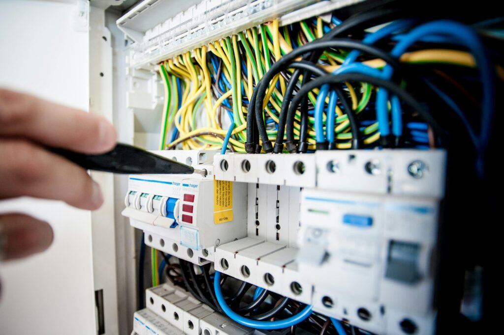 Smart Vara Hand of electrician working on a circuit breaker panel with colorful wires, ensuring safe electrical connections.